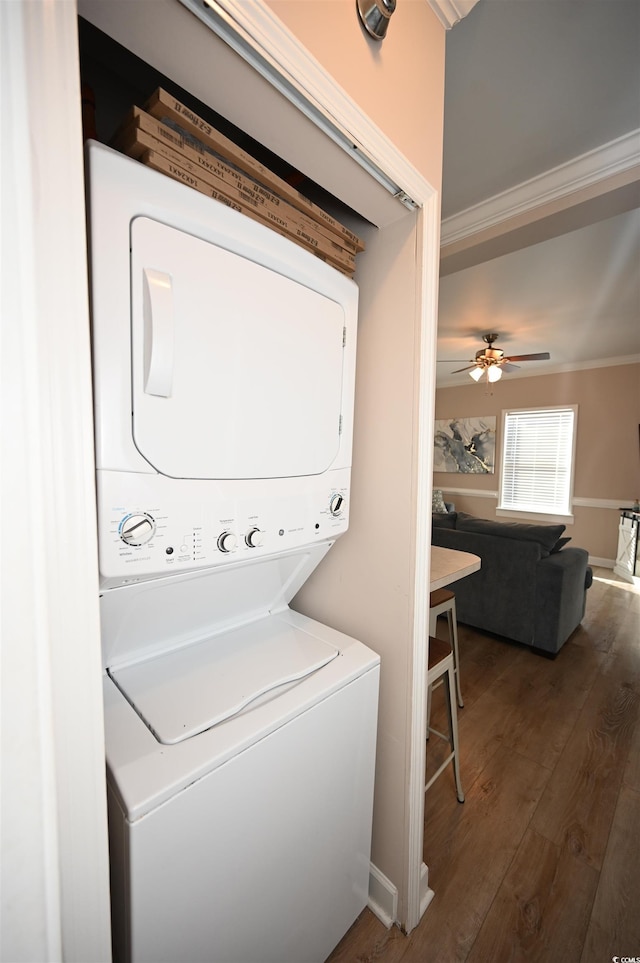 laundry area featuring stacked washer and dryer, ornamental molding, ceiling fan, and dark hardwood / wood-style flooring