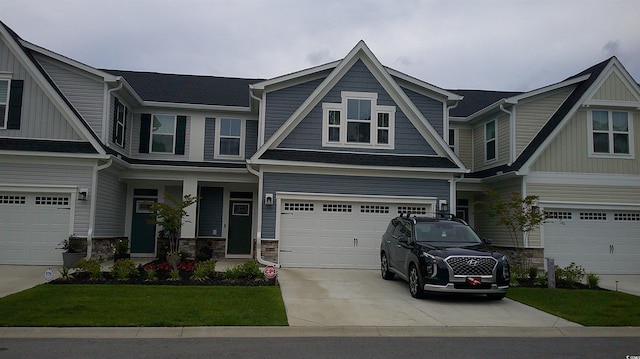 view of front of property featuring a garage, driveway, a front lawn, and stone siding