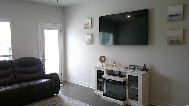 living room with a wealth of natural light, dark wood-style flooring, visible vents, and baseboards