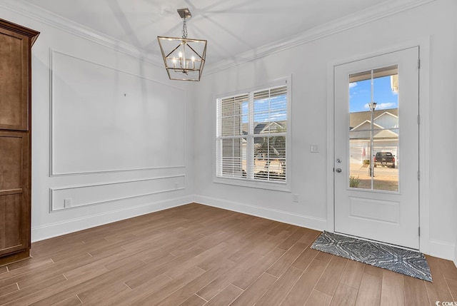 unfurnished dining area featuring an inviting chandelier, ornamental molding, light wood-type flooring, and plenty of natural light