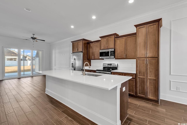 kitchen featuring sink, ceiling fan, stainless steel appliances, ornamental molding, and a center island with sink