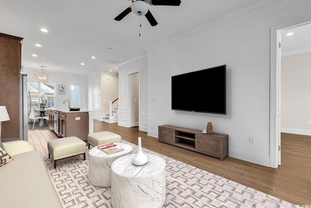 living room with ceiling fan, ornamental molding, and light wood-type flooring