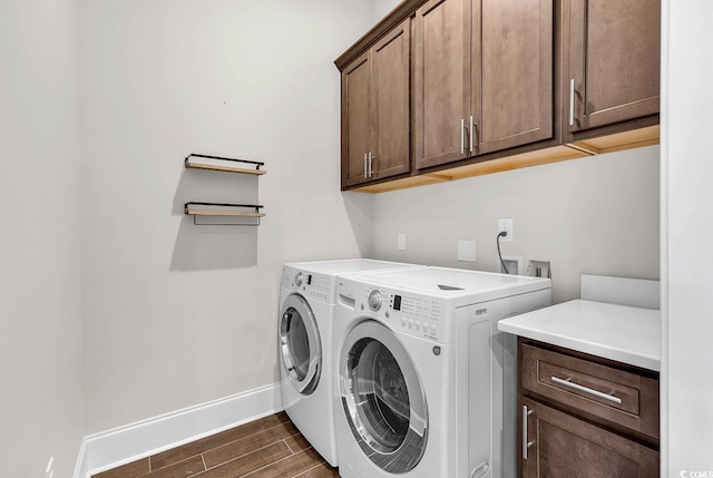 washroom with dark wood-type flooring, cabinets, and washing machine and dryer