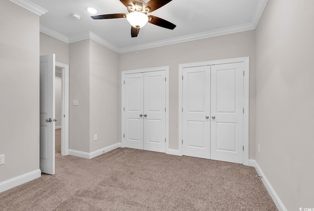 unfurnished bedroom featuring light carpet, two closets, crown molding, and ceiling fan