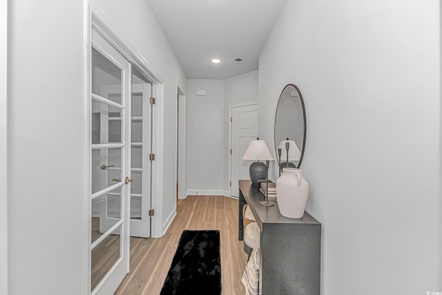 corridor featuring light wood-type flooring and french doors