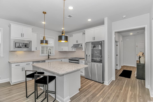 kitchen with pendant lighting, white cabinetry, sink, a center island, and stainless steel appliances