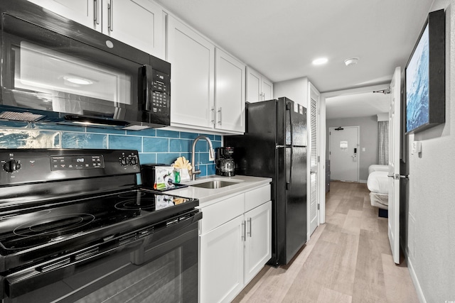 kitchen featuring tasteful backsplash, sink, white cabinets, light hardwood / wood-style floors, and black appliances