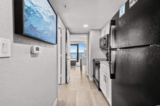 kitchen featuring white cabinetry, light hardwood / wood-style flooring, and black appliances