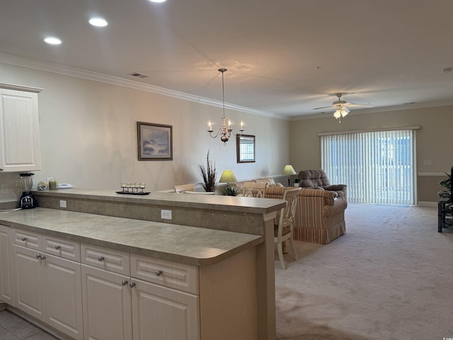 kitchen with hanging light fixtures, ornamental molding, and light colored carpet