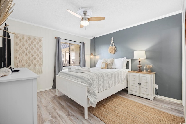 bedroom with ceiling fan, crown molding, light hardwood / wood-style floors, and a textured ceiling