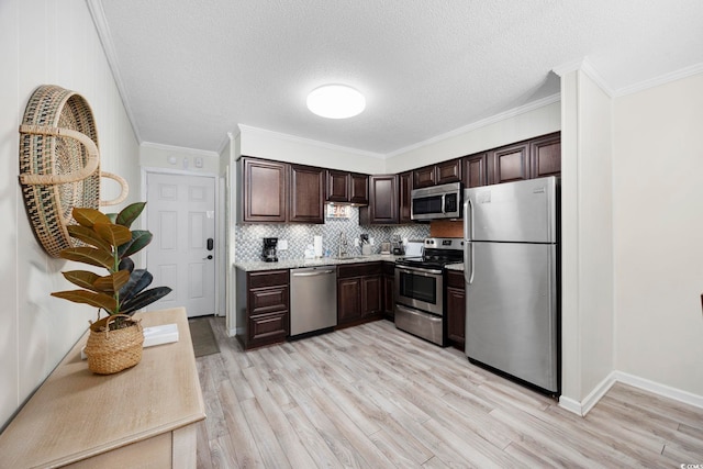 kitchen with dark brown cabinetry, light wood-type flooring, ornamental molding, stainless steel appliances, and backsplash