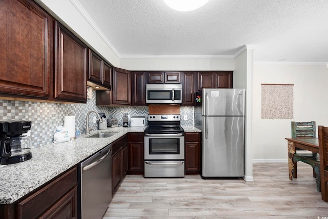 kitchen with appliances with stainless steel finishes, tasteful backsplash, sink, light stone countertops, and light hardwood / wood-style flooring