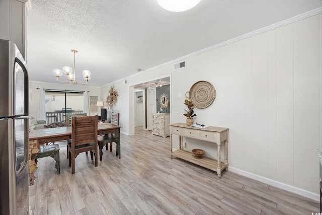 dining space with a notable chandelier, crown molding, light hardwood / wood-style flooring, and a textured ceiling