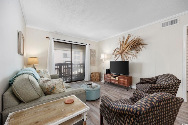 living room with ornamental molding, light hardwood / wood-style floors, and a textured ceiling