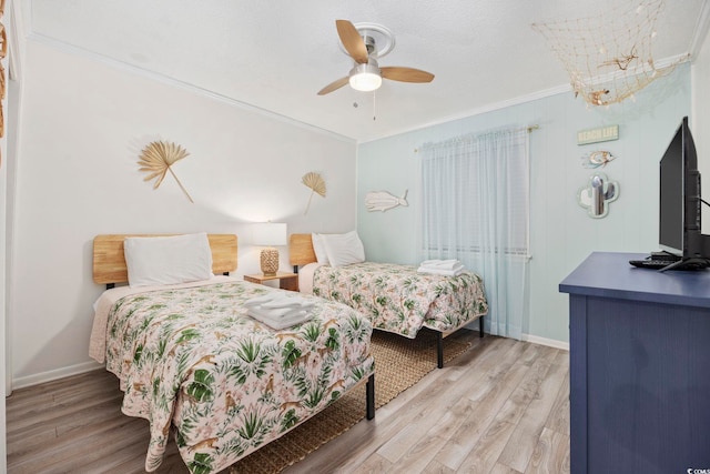 bedroom with light hardwood / wood-style flooring, ornamental molding, and ceiling fan