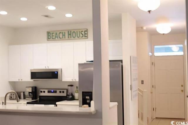 kitchen featuring appliances with stainless steel finishes, light stone countertops, sink, and white cabinets