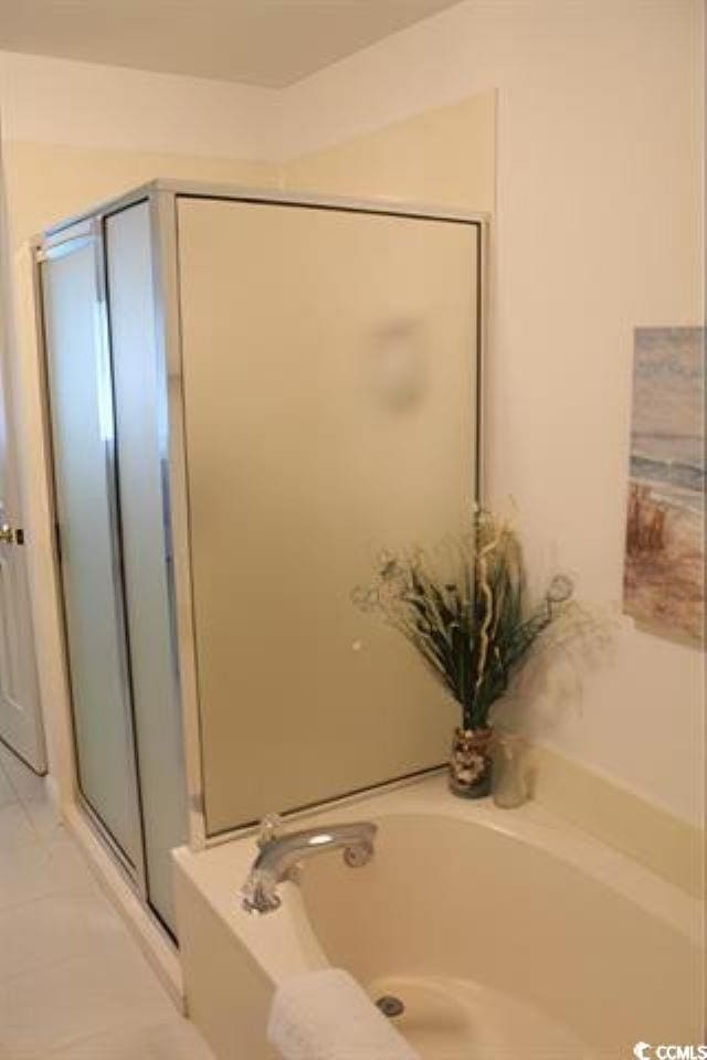 bathroom with independent shower and bath and tile patterned flooring