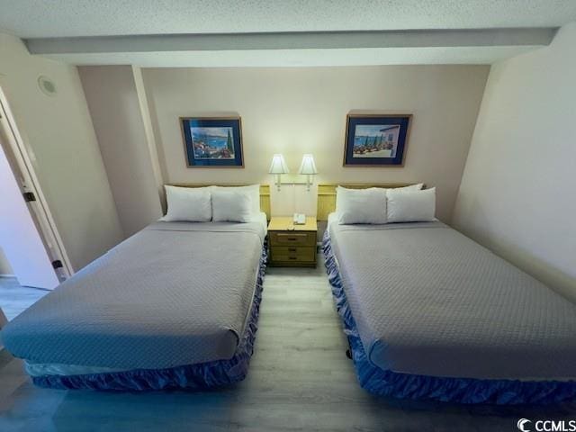 bedroom featuring beamed ceiling and light wood-type flooring