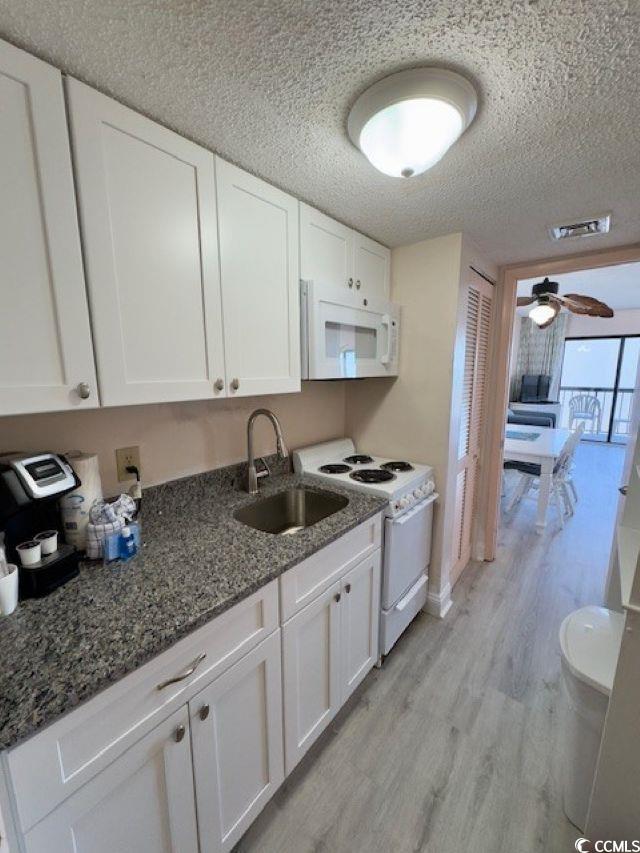 kitchen with light wood-type flooring, white appliances, sink, and white cabinets