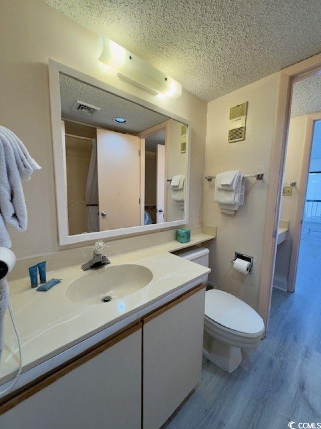 bathroom with vanity, hardwood / wood-style floors, a textured ceiling, and toilet