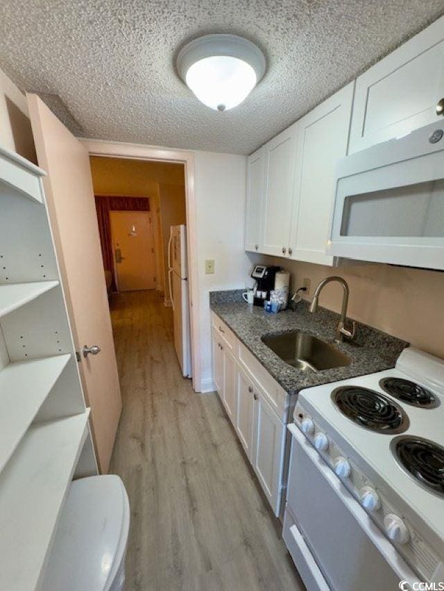 kitchen with white appliances, light hardwood / wood-style floors, sink, and white cabinets