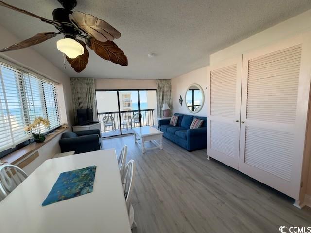 living room with ceiling fan, wood-type flooring, and a textured ceiling