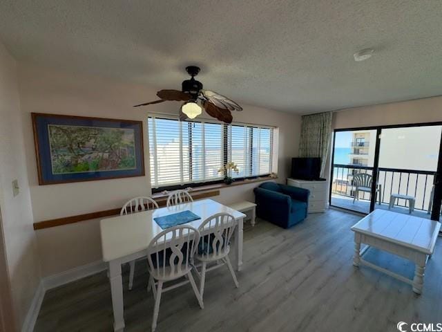 dining space with ceiling fan, hardwood / wood-style flooring, and a textured ceiling