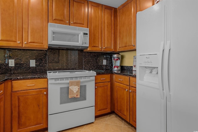 kitchen featuring backsplash, white appliances, dark stone counters, and light tile patterned floors