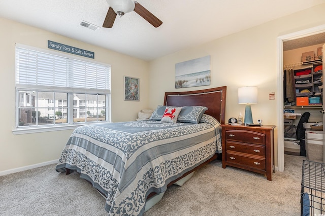 bedroom with ceiling fan, light colored carpet, a spacious closet, and a closet