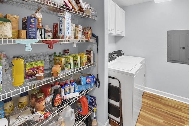 laundry room featuring hardwood / wood-style flooring, washing machine and clothes dryer, electric panel, and cabinets