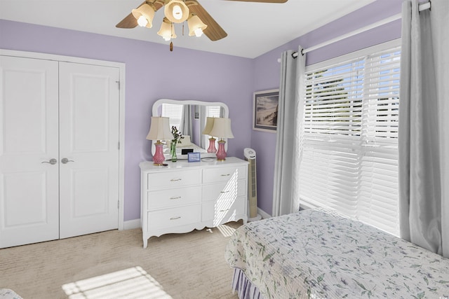 bedroom with ceiling fan, light colored carpet, and a closet