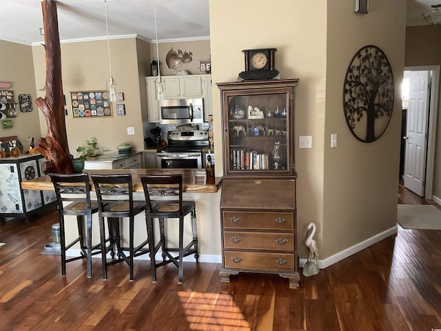 kitchen featuring ornamental molding, stainless steel appliances, kitchen peninsula, and a breakfast bar