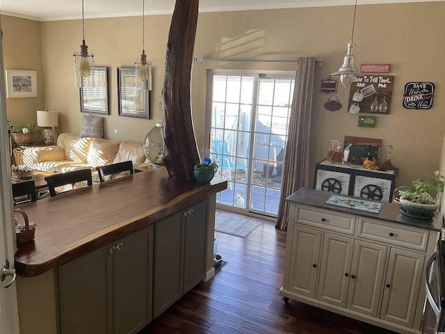 kitchen featuring butcher block countertops, hanging light fixtures, crown molding, and dark wood-type flooring