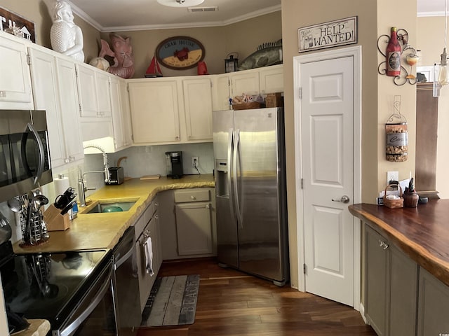 kitchen featuring dark wood-type flooring, sink, white cabinetry, ornamental molding, and stainless steel appliances