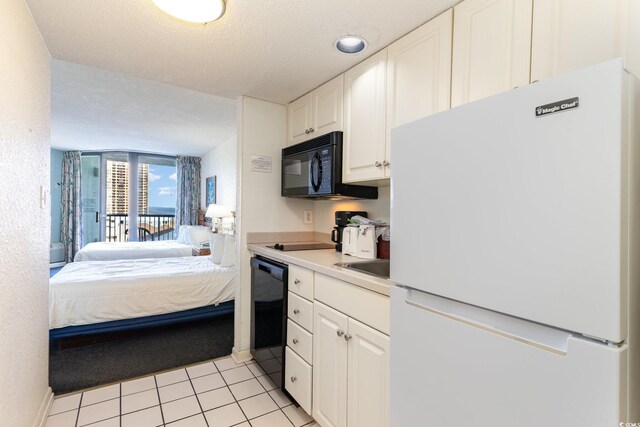 9550 Shore Dr Unit 722, Myrtle Beach, SC 29572 - kitchen featuring light tile patterned floors, a textured ceiling, black appliances, and white cabinets