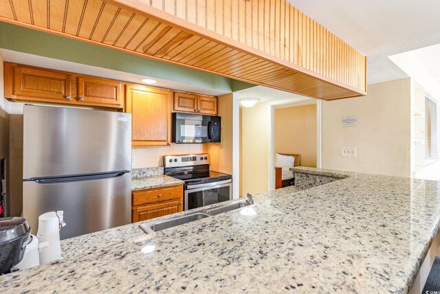 kitchen featuring light stone counters, stainless steel appliances, and kitchen peninsula