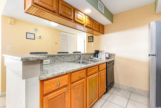 kitchen with light tile patterned floors, sink, stainless steel fridge, dishwasher, and light stone countertops