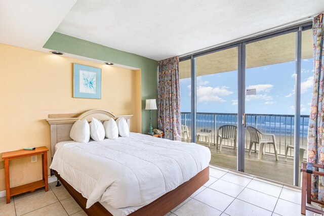 tiled bedroom with access to exterior, a wall of windows, a beach view, and a water view