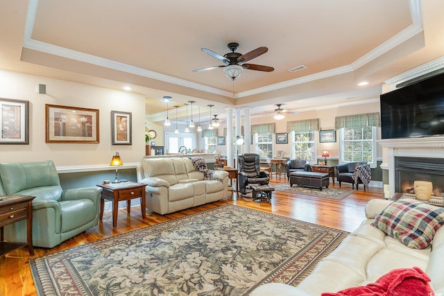 living room with a tray ceiling, ornamental molding, and hardwood / wood-style flooring