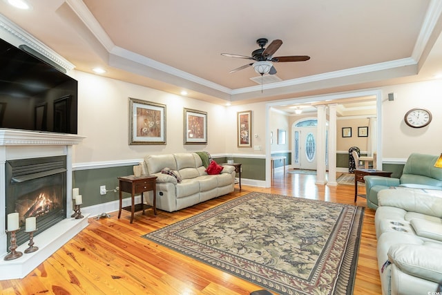 living room featuring hardwood / wood-style flooring, ceiling fan, ornamental molding, and ornate columns