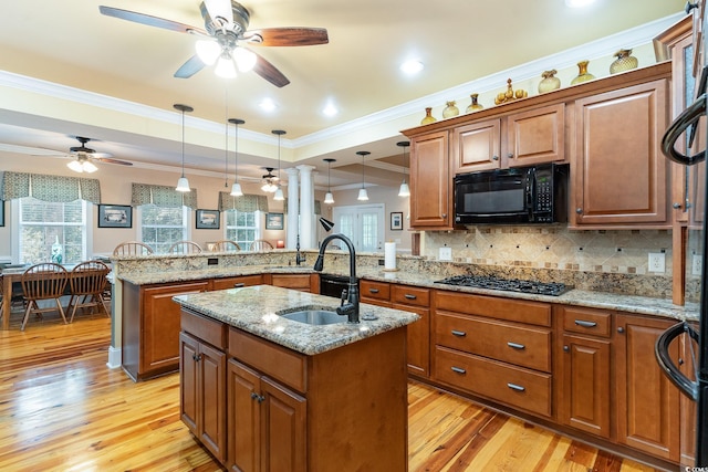 kitchen featuring black appliances, sink, a kitchen island with sink, kitchen peninsula, and a raised ceiling