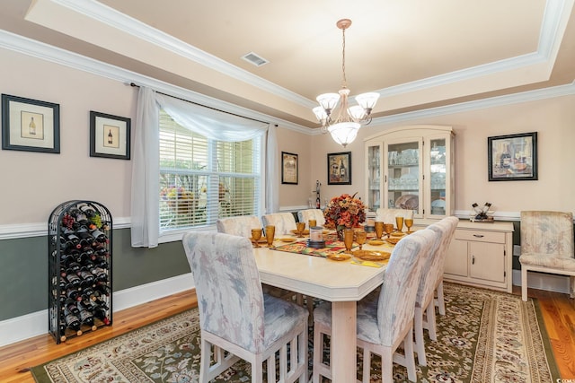 dining space featuring crown molding, a tray ceiling, light hardwood / wood-style floors, and a chandelier