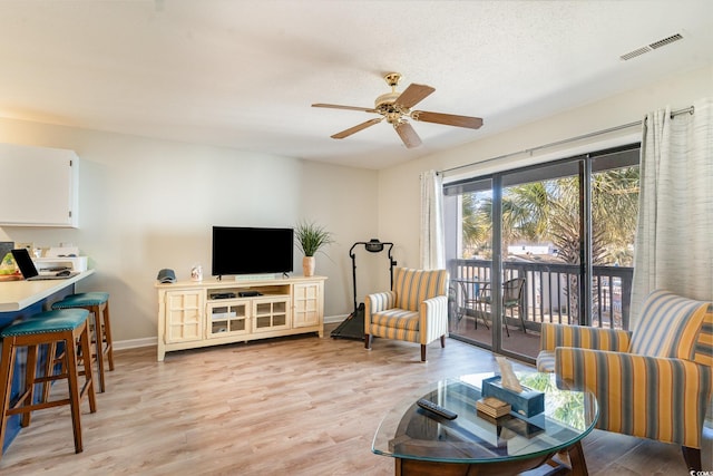 living room with a textured ceiling, light hardwood / wood-style flooring, and ceiling fan