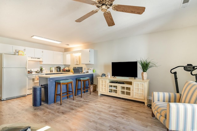 kitchen with white cabinetry, white appliances, kitchen peninsula, and a breakfast bar area