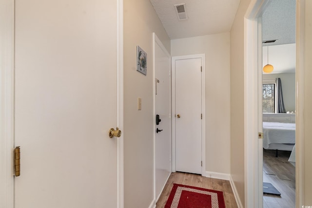 hall featuring a textured ceiling and light wood-type flooring