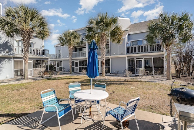 exterior space with a balcony, a sunroom, a yard, and a patio area