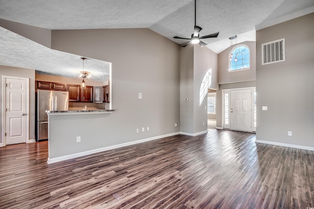 unfurnished living room featuring ceiling fan, dark hardwood / wood-style floors, high vaulted ceiling, and a textured ceiling