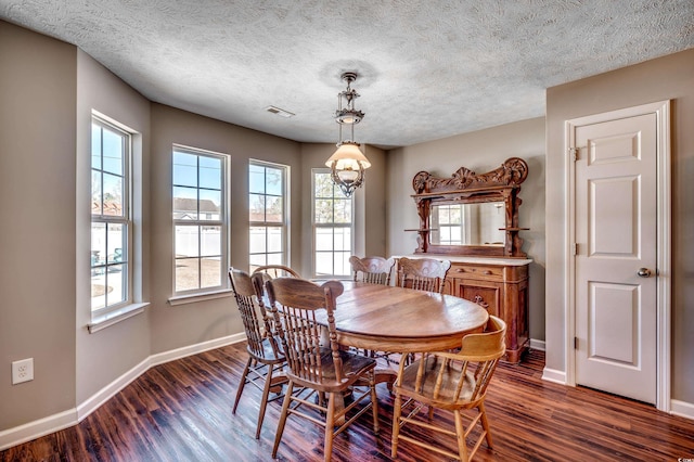 dining space featuring dark wood-type flooring, a textured ceiling, and an inviting chandelier