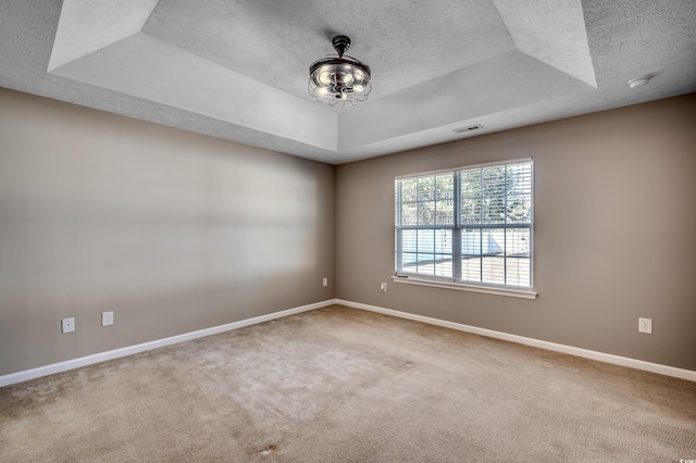 unfurnished room featuring a tray ceiling and carpet