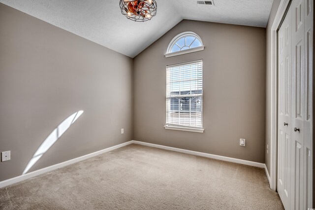 empty room featuring lofted ceiling and carpet